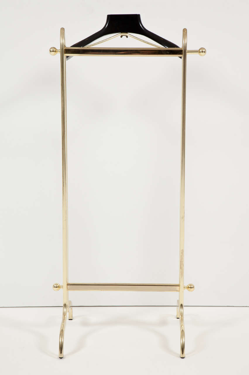 Elegant and refined Mid-Century Modern brass-plated men's valet with black lacquered coat hanger. Sturdy, solid and heavy, this valet is in excellent condition. This vintage piece is on display on the 1stdibs showroom at the New York design center