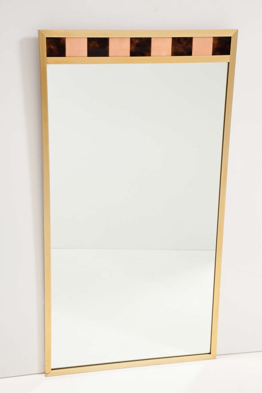 Brass-framed rectangular mirror with ceramic tile detail.  USA, circa 1960.  A half-inch wide brushed brass frame is complemented by inlaid pale orange and maroon tiles.

Dimensions: 24”W x 44”H x 3/4" D