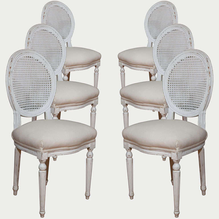 These white oval cane back chairs with their generously crowned seats will keep you comfortable for hours of dining. Fluted, straight legs preserve a clean, uncomplicated line that blends with almost any table. The classic formality of these chairs