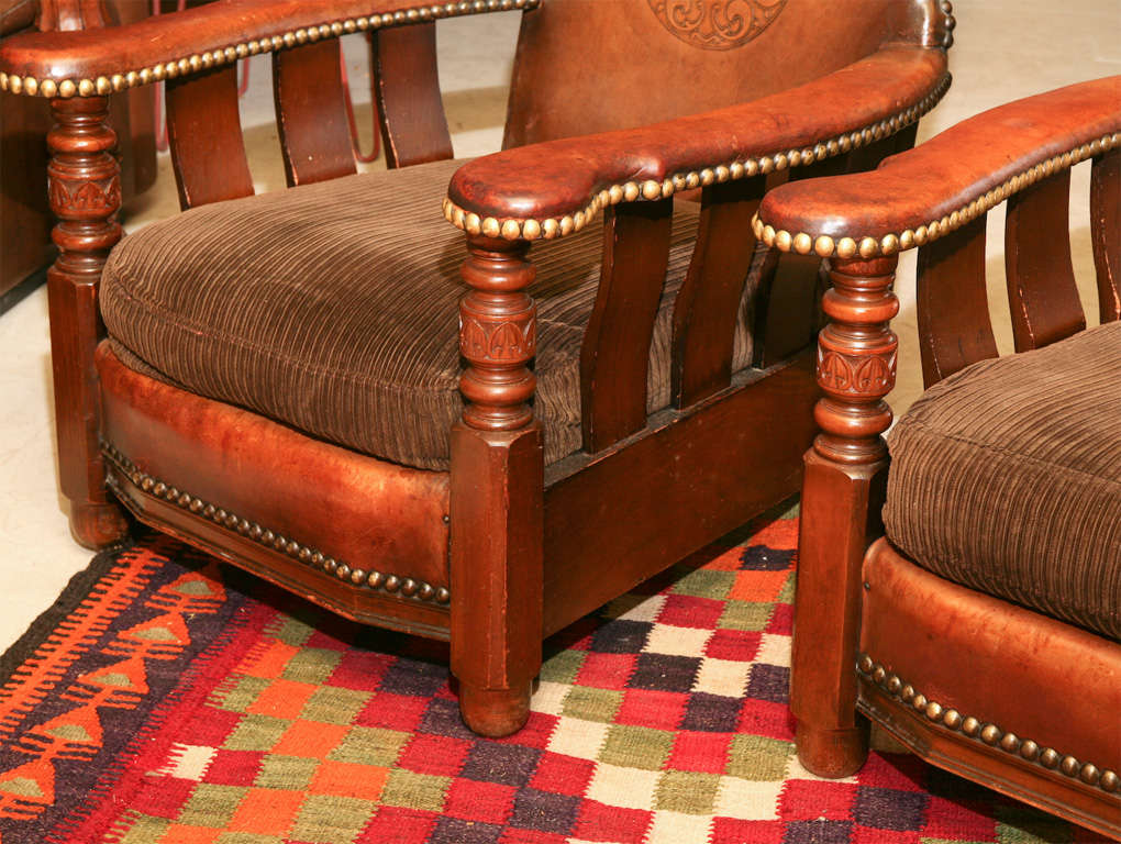 Comfy pair of embossed leather club chairs, with corderoy cushions, brass studs and wood frames