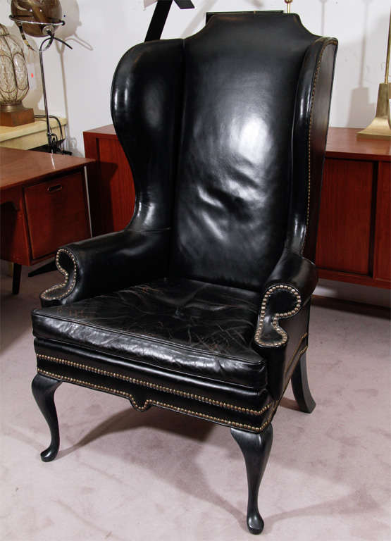 Vintage wing chair in black leather with metal stud trim.