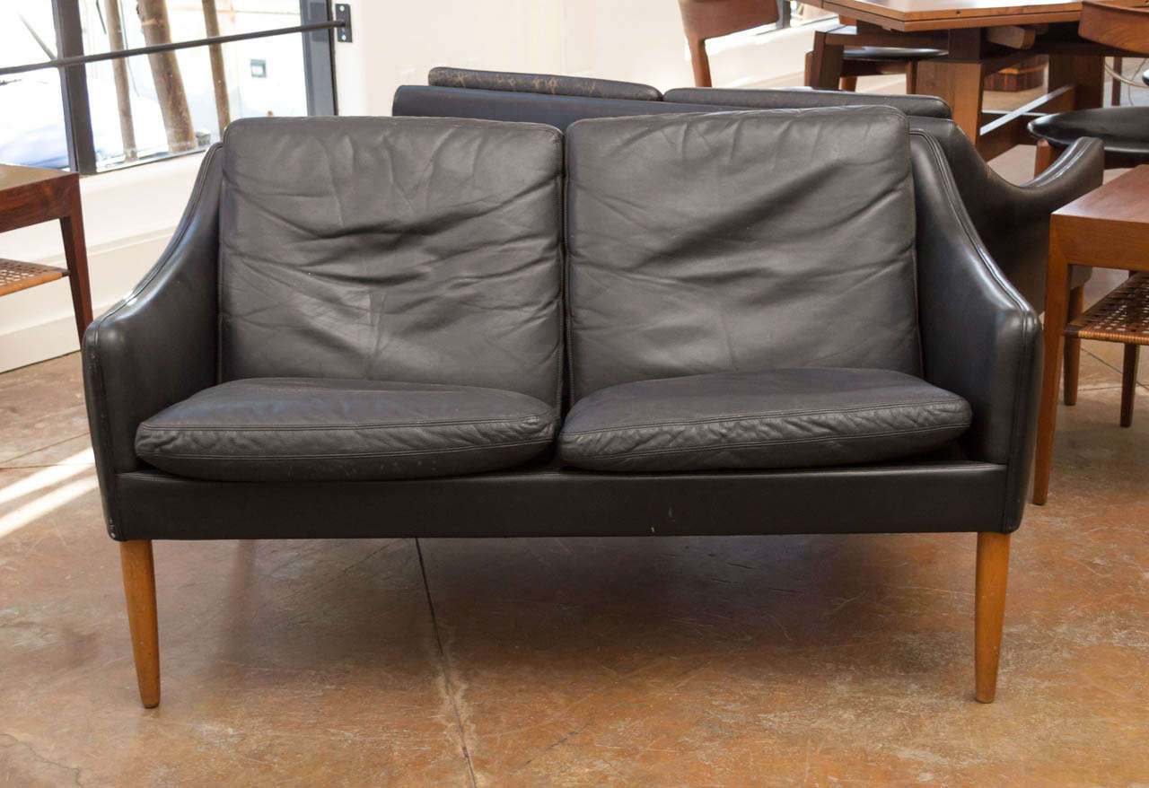 A two seater sofa upholstered with black leather. Round tapered teak legs, with four loose cushions. Model 800 / Designed in 1956.
Literature : Mobila Dansk #137, 1963.