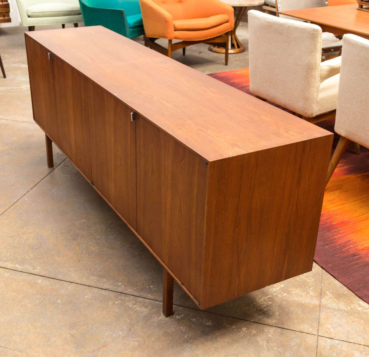 A low wooden credenza (Style # 541) by Florence Knoll. Four cabinets, which open up to two large cubbies of maple (adjustable shelves included), left side with slide out drawers. Chromed pulls. Part of the Original production run with wood legs.
