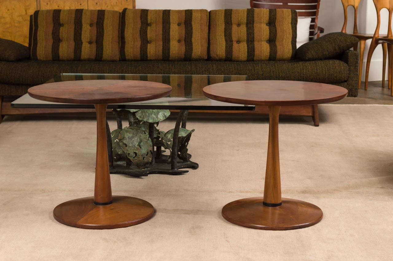 A pair of walnut side tables in the Manner of Nanna Ditzel with round table top and base. Single walnut leg tapers in and flares where it joins the top. Beautiful grain.