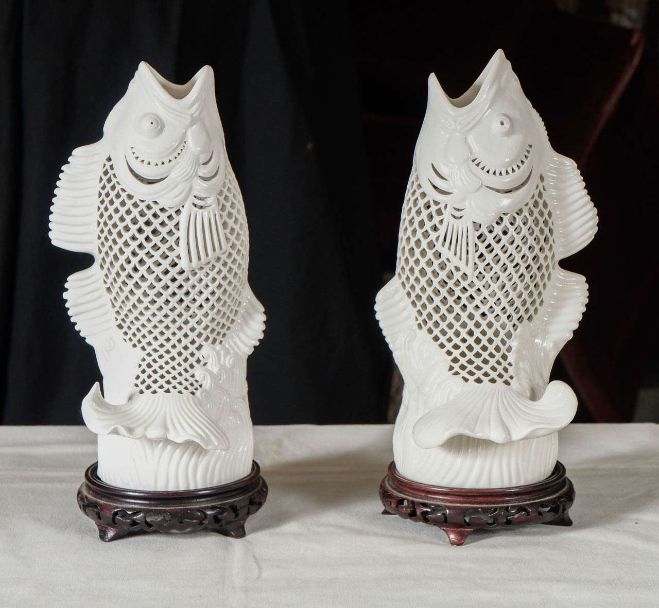 This lovely pair of Blanc De Chine fish formed of porcelain that has been carved and pierced to allow light and creating the fish scale pattern. Made in a left and a right  manor creating a  mirrored pair. The modeling is lively and the carp in fact