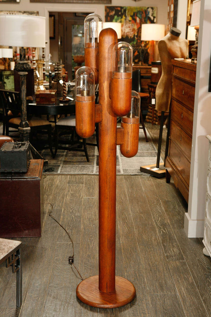 A wooden floor lamp in the shape of a cactus with glass globe shades.