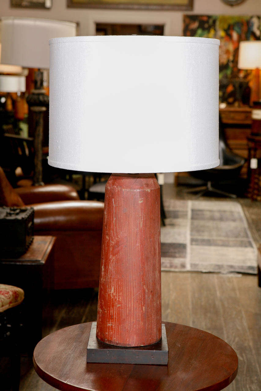 A antique painted wooden foundry element wired and mounted as a table lamp with a custom linen shade.