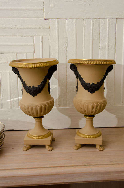 Attractive pair of matte beige pottery neoclassical urns with gilt trim