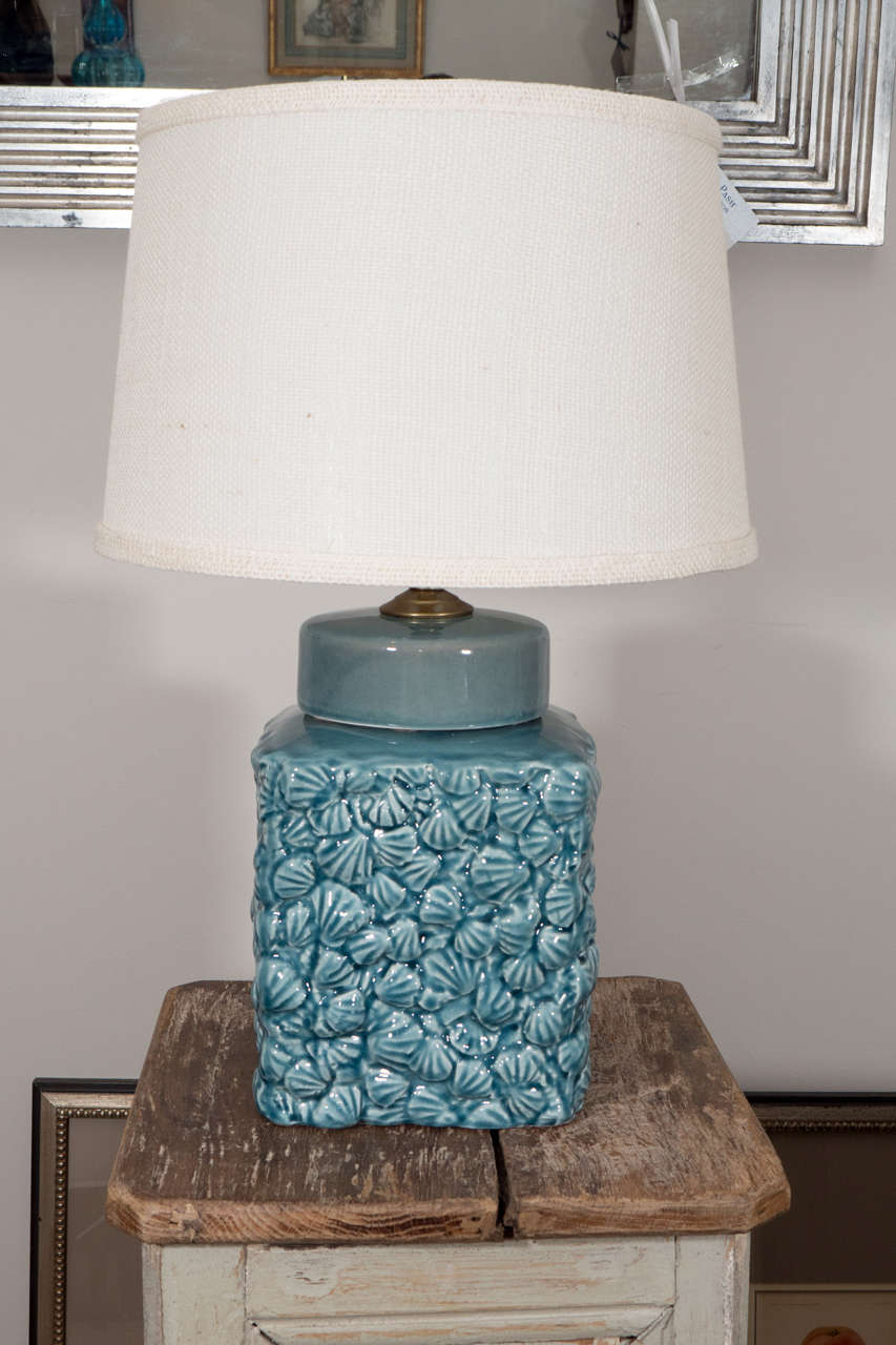 A pair of small, square ceramic table lamps in a beautiful blue with a shell motif.