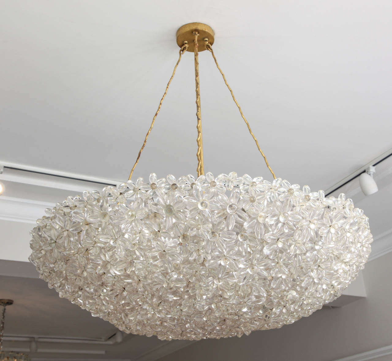 This stunning piece is made up of lucite daisies that are joined together, creating a lovely half-moon bouquet with light passing through it.  The piece is hung from three 