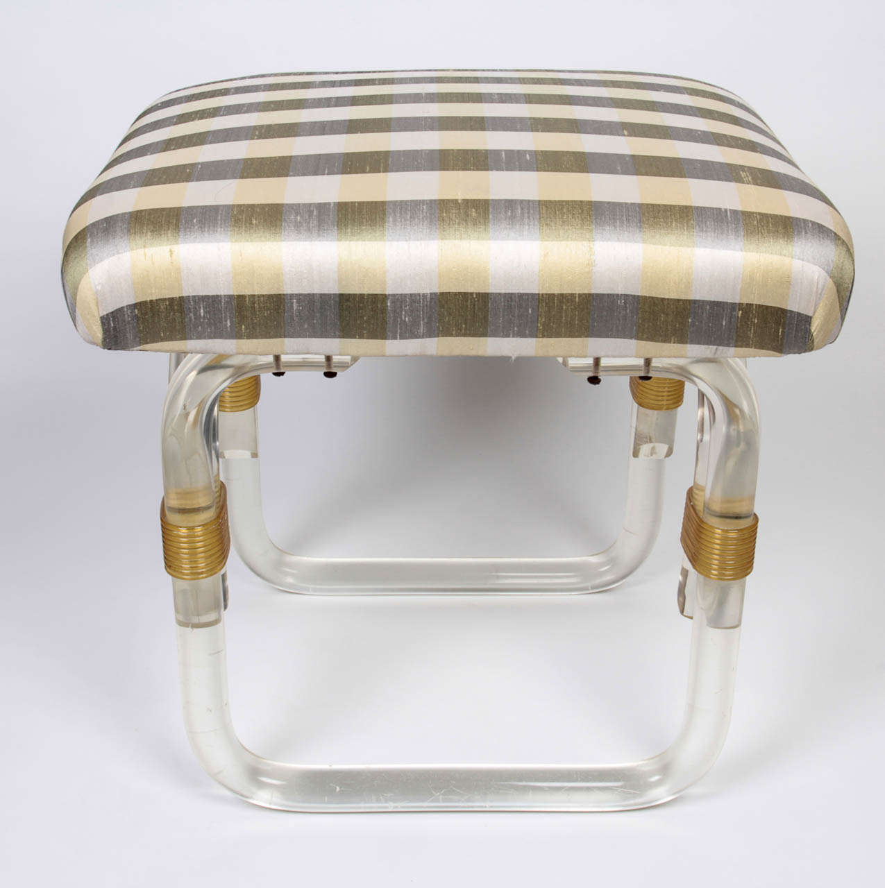 Grosfeld House New York lucite stool circa 1940.  Cylindrical lucite base stool with gold lucite wrap like connecting elements, silk upholstery.

H: 16 1/4