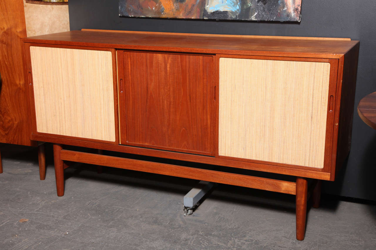 Vintage 1950s Henrik Wortz Danish Sideboard

Teak and rush sideboard by well respected cabinetmaker Henrik Wortz.  Features 3 sliding teak doors; 2 with a layer of reed. Great for the living room as a media cabinet, in the dining room as a buffet,