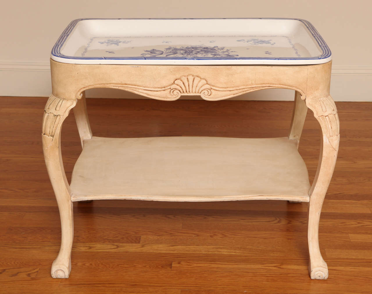 Stunning blue and white porcelain tray decorated with blowsy floral sprays, signed Rörstrand, Sweden's oldest porcelain manufacturers and dated 1924, set into a cream-painted table carved with shell decoration and raised on cabriole legs with a