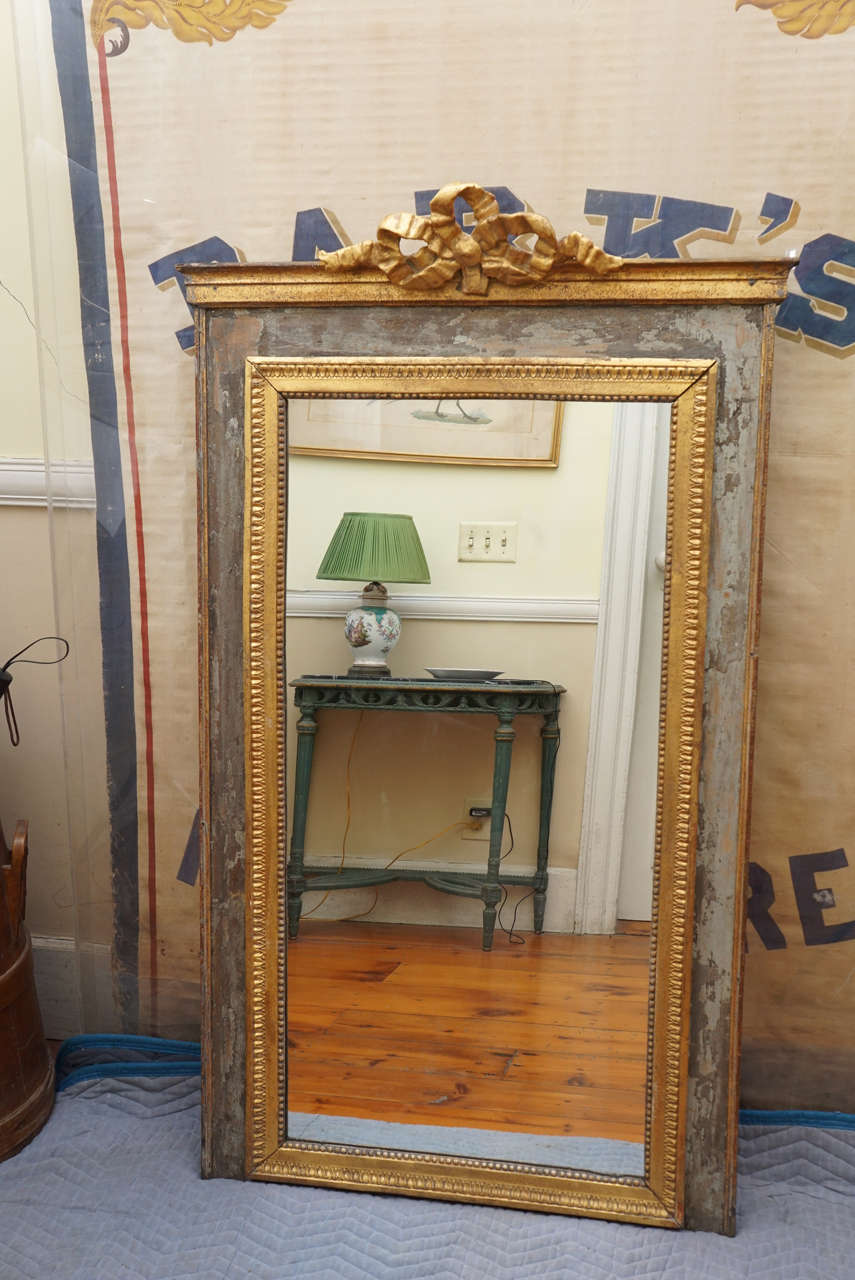Handsome classical grey painted and parcel-gilt large French mirror. Beautifully
carved and gilded bow at the crest of the mirror and gilded carving frame the
glass.