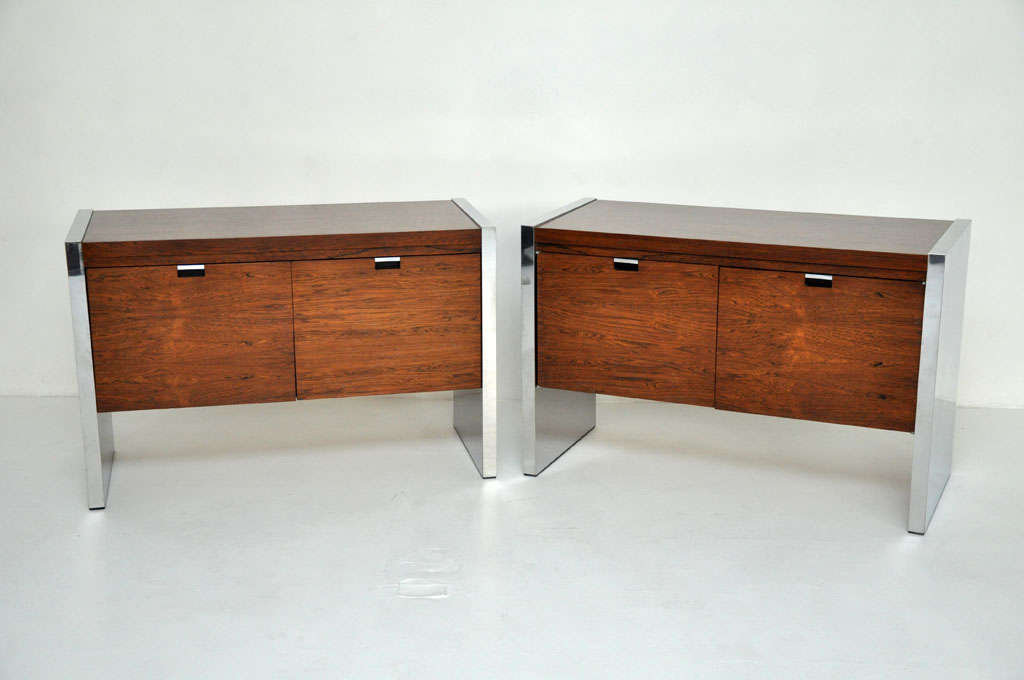 Pair of chests or sideboards by Roger Sprunger for Dunbar. Rosewood cases with stainless steel sides. One cabinet has two doors, the other two drawers.
