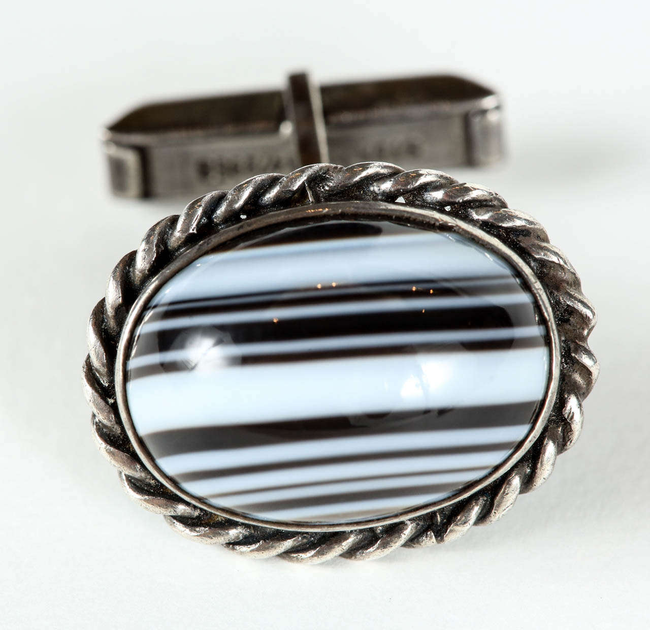 A classic pair of cufflinks with an oval agate cabochon framed within a sterling rope detail. Stamped 