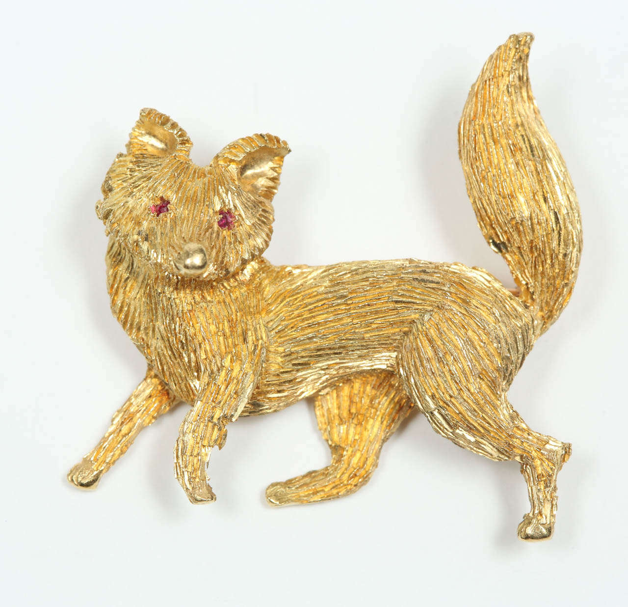 A whimsical and nicely detailed 18k gold fox pin with ruby eyes.