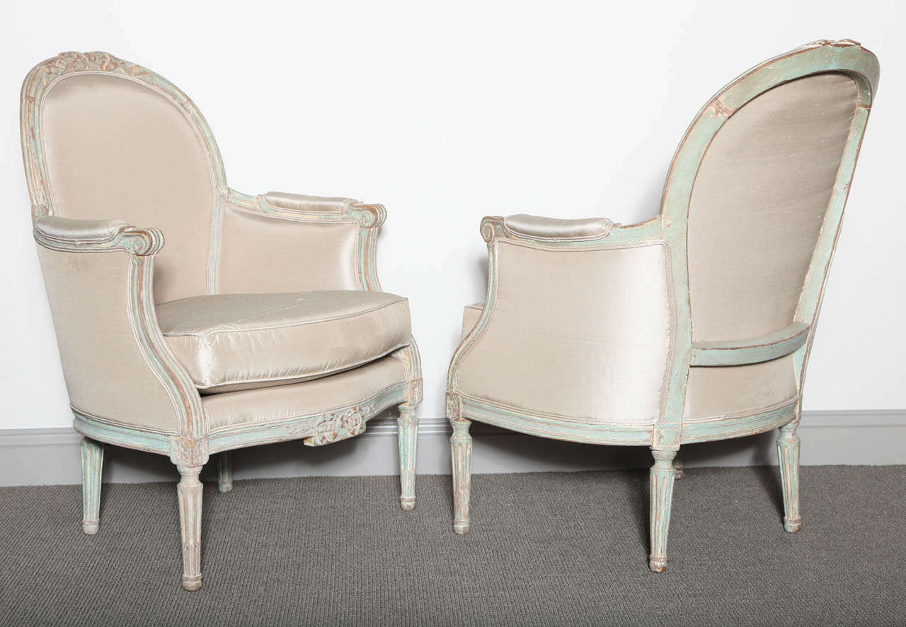 Pair of armchairs in the Gustavian style, with delicate ribbon carving, fluted arms, carved apron and corner blocks on turned tapering legs. Upholstered in silk.