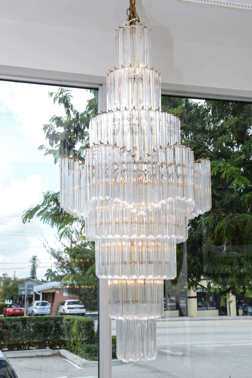 This impressive 5 1/2'L chandelier boasts 8 tiers of half round Lucite rods suspended from brass pegs. Scalloped center tier pairs with angled edge straight line tiers.