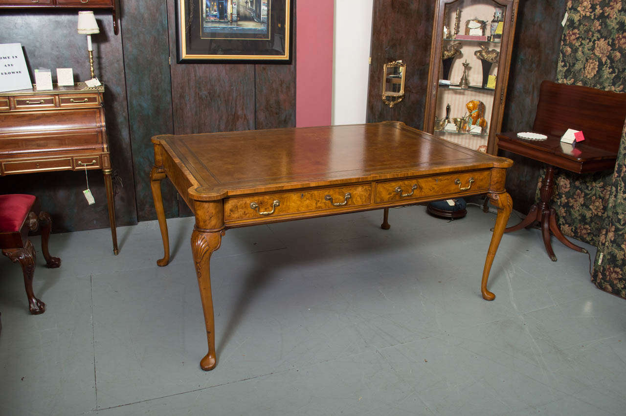 An English circa 1850's Walnut partners desk, with inset tooled leather top, burled Walnut details and cabriolet legs, with shell carved knees. Pair of drawers on each side.  
Measurement from floor to underside 24 inches.