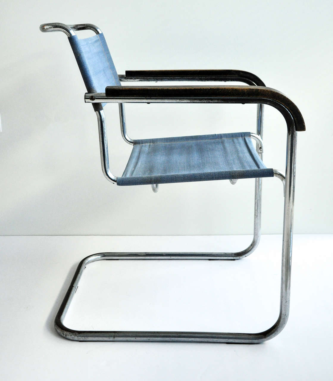A cantilevered tubular steel armchair with wood armrest originally designed  in 1928 for Thonet by the modernist architect and furniture designer Marcel Breuer (1902-81). This chair is a variation of the B34 armchair. Blue Eisengarn fabric (a stiff