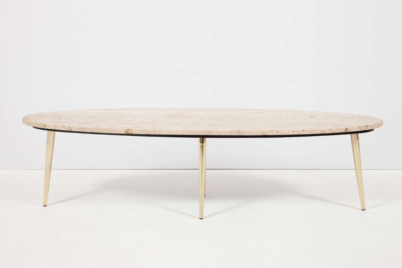Elongated oval travertine top supported by spiky polished brass legs. Pure Mid-Century Italian form.