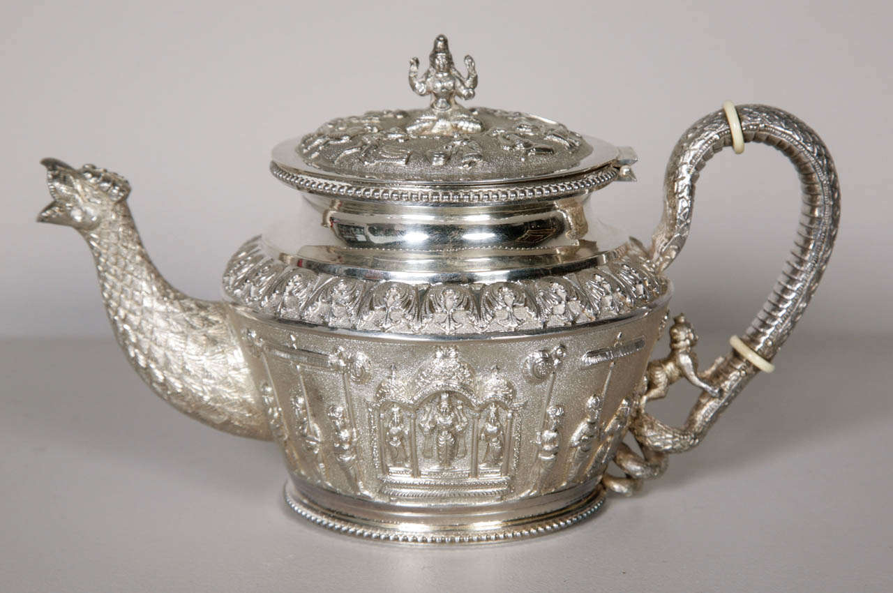 a three-piece silver teaset comprising of a teapot, sugar bowl and milk jug depicting the ritual procession of Puri - quite possibly representing the story of Vishnu's descent onto earth. Decorated with Hindu deities and mythological figures carved