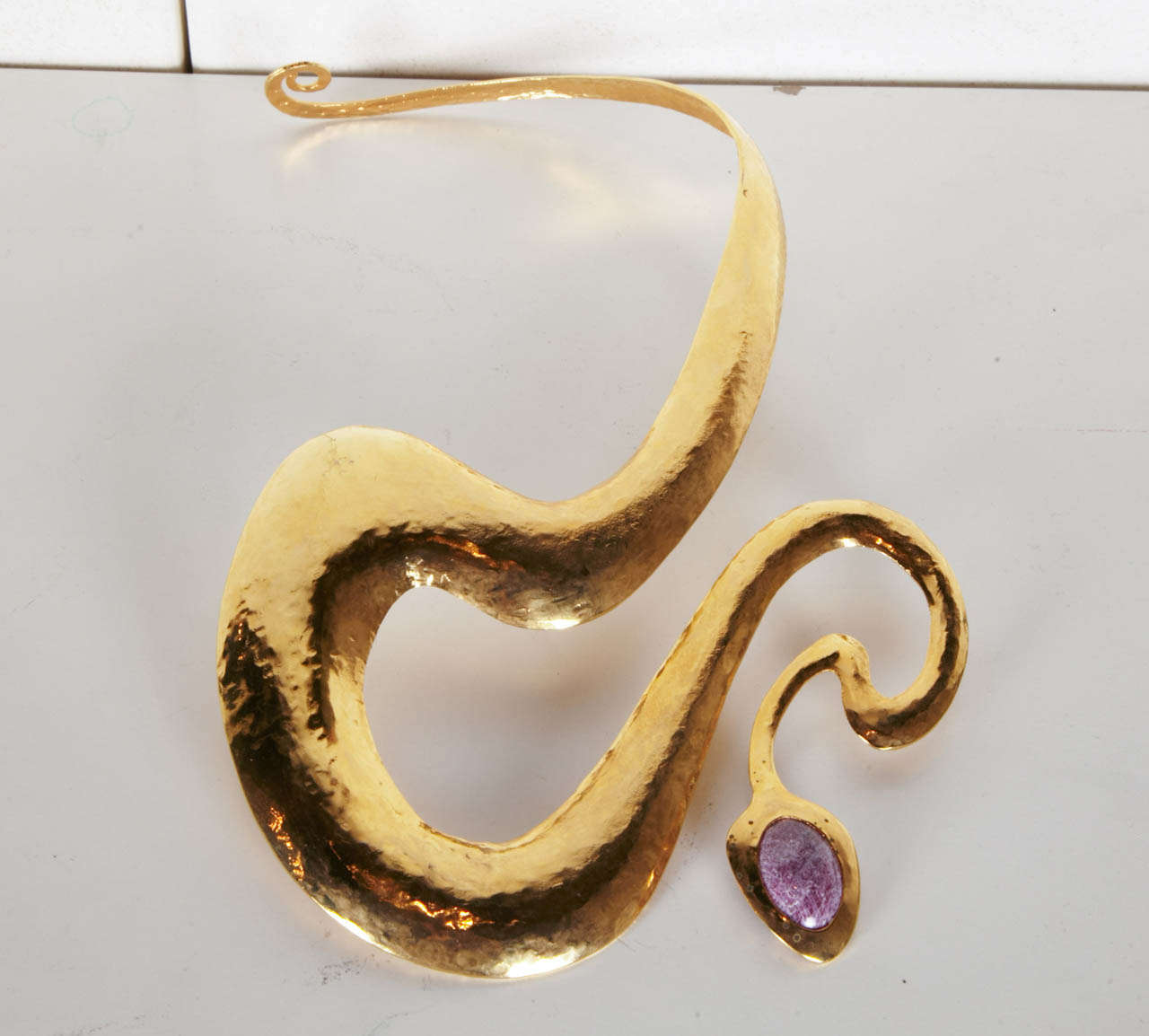 Important sculpture necklace in gold hammered metal, representing a snake, the head is decorated with a violet jasper.
Signed and numbered 1/4 EA (Artist proof)
Certificate.