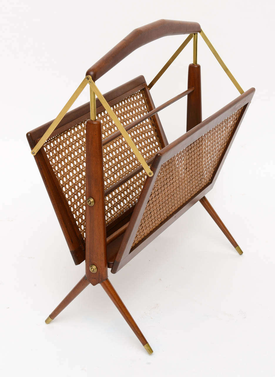 Very tailored mid-century design attributed to Ico Parisi, this walnut, brass and caned magazine rack or holder is high Italian styling.  Featuring sides that fold in when picked up by the handle.  In excellent condition with reglueing to legs.  One