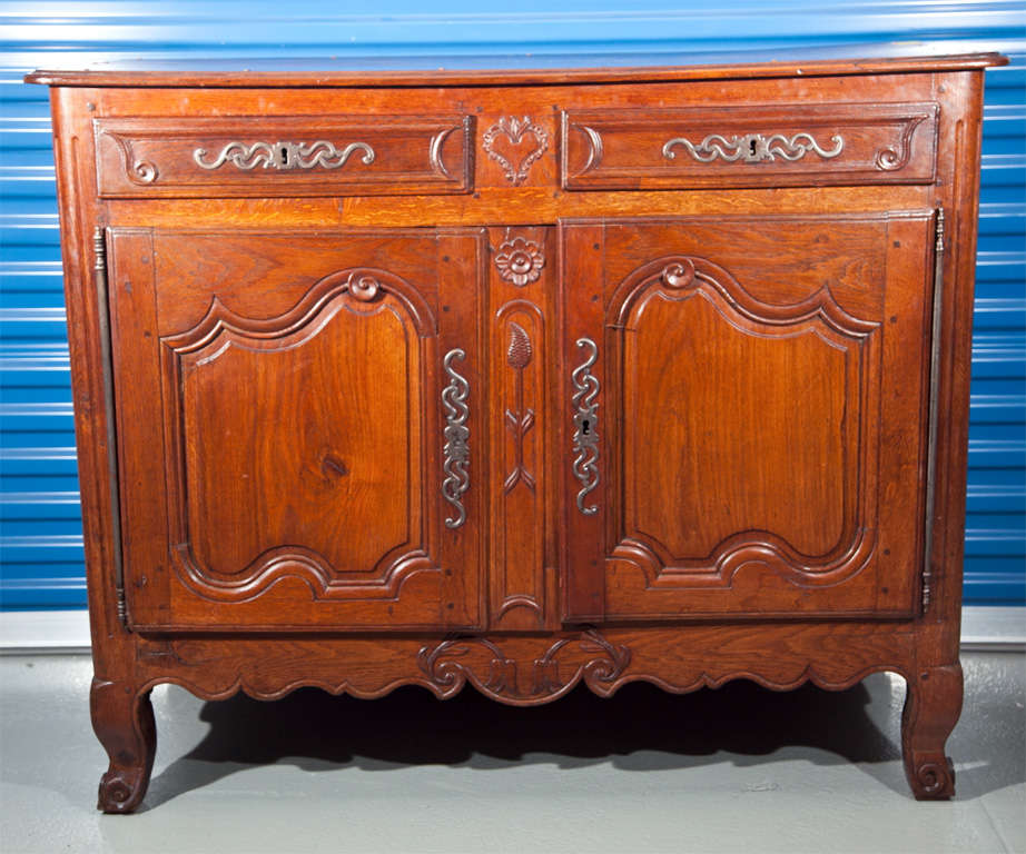 Delicately hand-carved solid cherrywood with wrought iron hardware. Richly grained wood in a deep cognac tone.