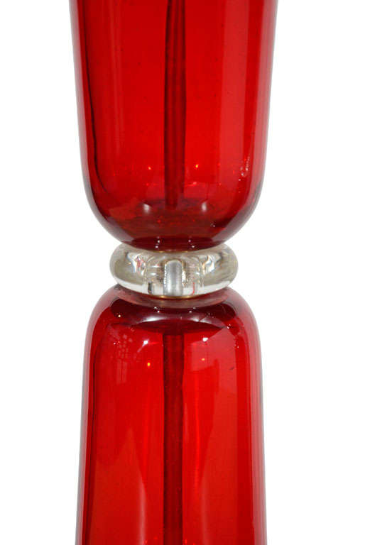 An exquisite pair of hourglass-form, blown glass table lamps in a stunning ruby-red with rounded, clear glass centers and thick, chamfered glass bases. The polished chrome tops and hardware add a modern touch and the pair has been newly rewired with