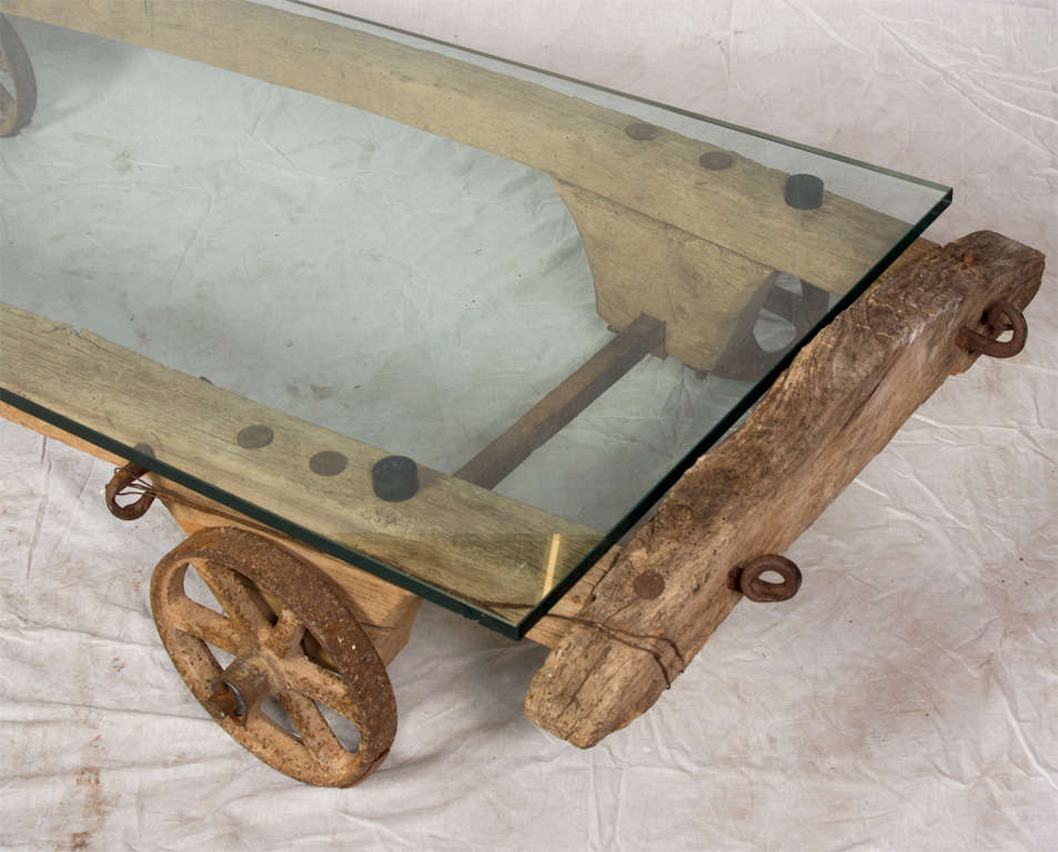 Merveilleuse grande table basse avec plateau en verre.  Fabriqué à partir d'un vieux chariot en bois du 19e siècle avec des roues en métal.