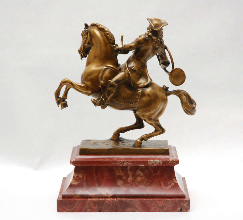 A turn-of-the-century bronze sculpture of a horse and rider, by Austrian sculptor Hans Müller (1873-1937) The uniformed rider is carrying a horn in one hand and the reins in the other and the sculpture is mounted on a red marble base. The sculpture