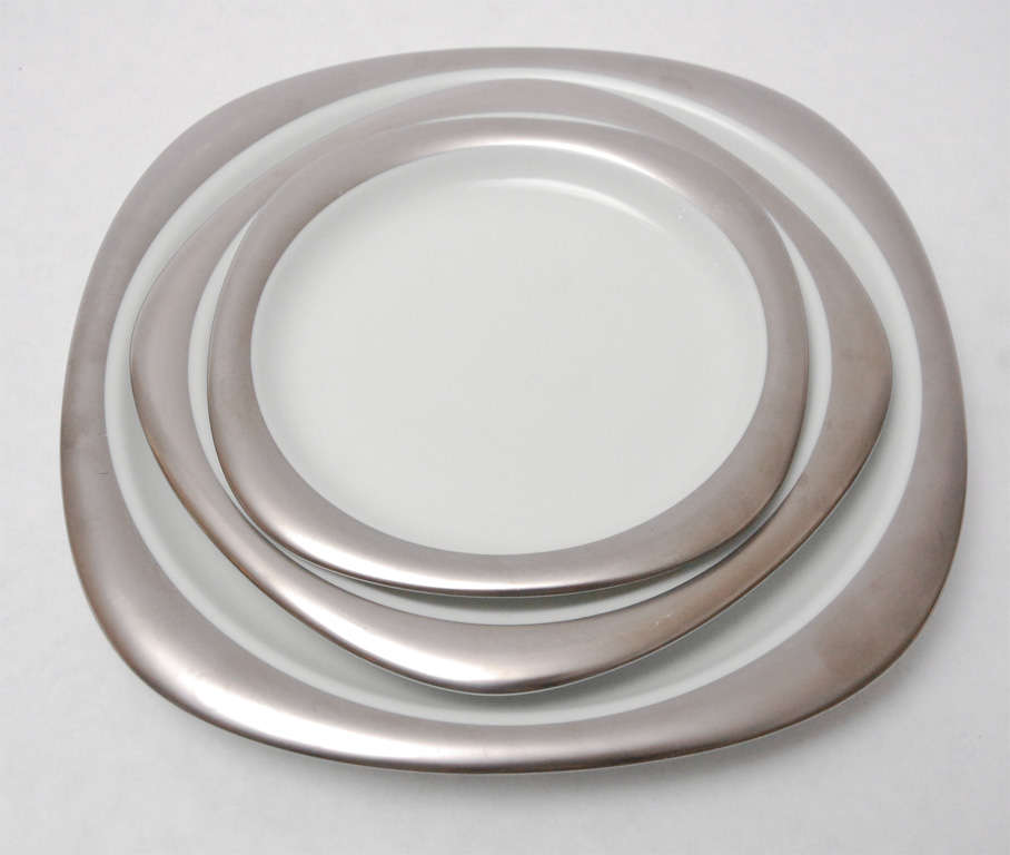 A beautiful set of eight place settings of Rosenthal Studio-Line's limited edition 100th Anniversary china, composed of rounded square platinum edged bread, salad and dinner plates and a cup and saucer. Dimensions given below are for the dinner