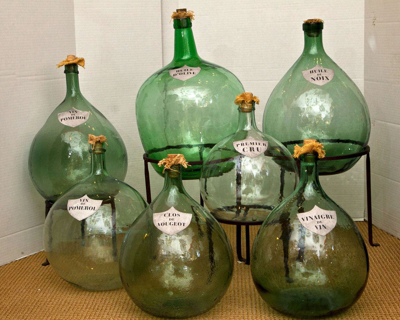 A collection of 7 hand blown and labeled French wine storage jars. Various sizes and shapes, all with cork and burlap stops.
The wrought iron stands are included.