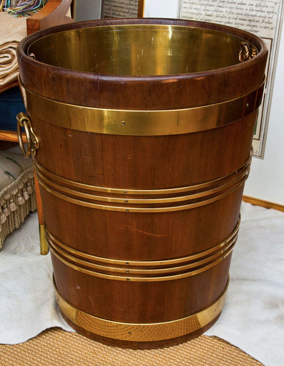 A beautifully crafted slatted wood bucket bound by solid brass rings. There are two large ring handles on either side. Within the bucket sits a liner of sheeted brass, also with handles.