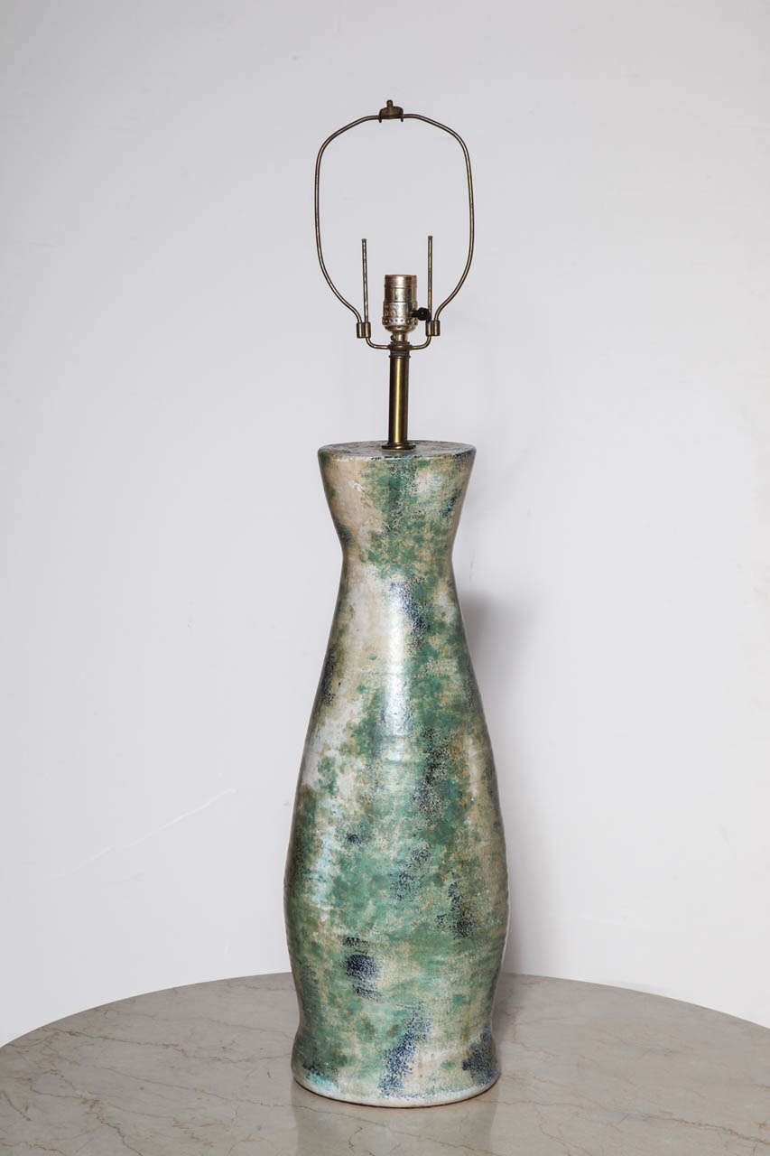 Circa 1950's massive corseted bottle form ceramic lamp with beige background, green, blue and white accents with satin glaze.