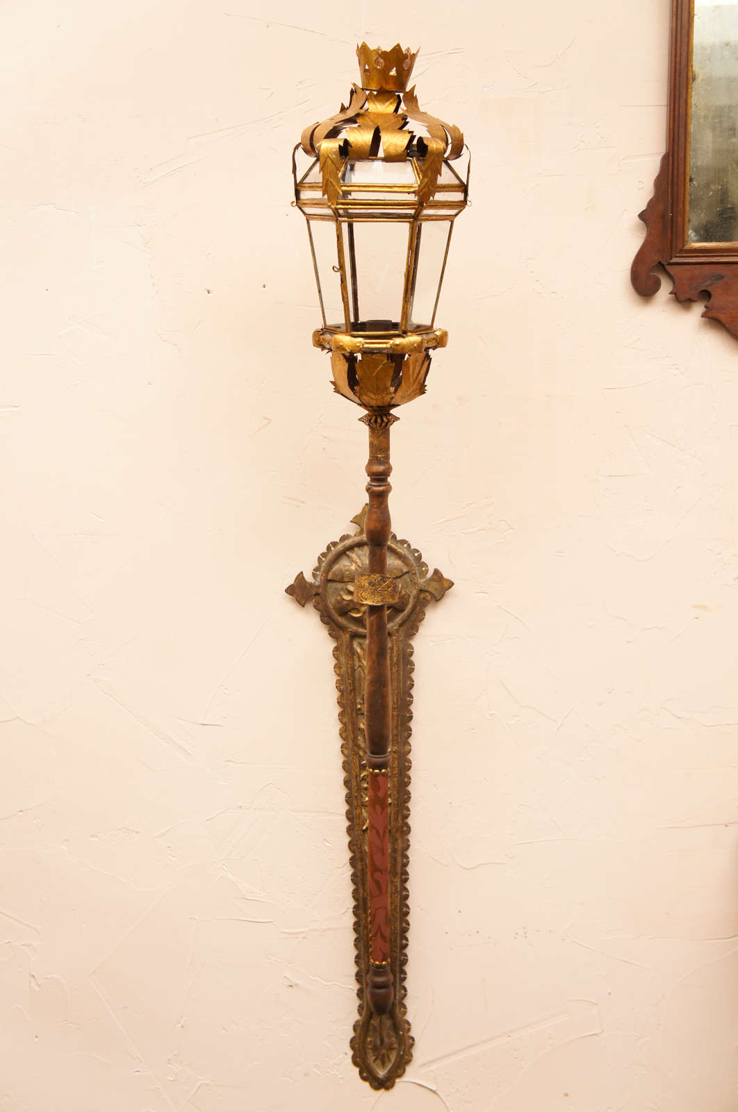 Highly decorative gold gilt recently electrified lanterns held up by carved wood support.  Can be wall mounted.  Backplate measures 8.75