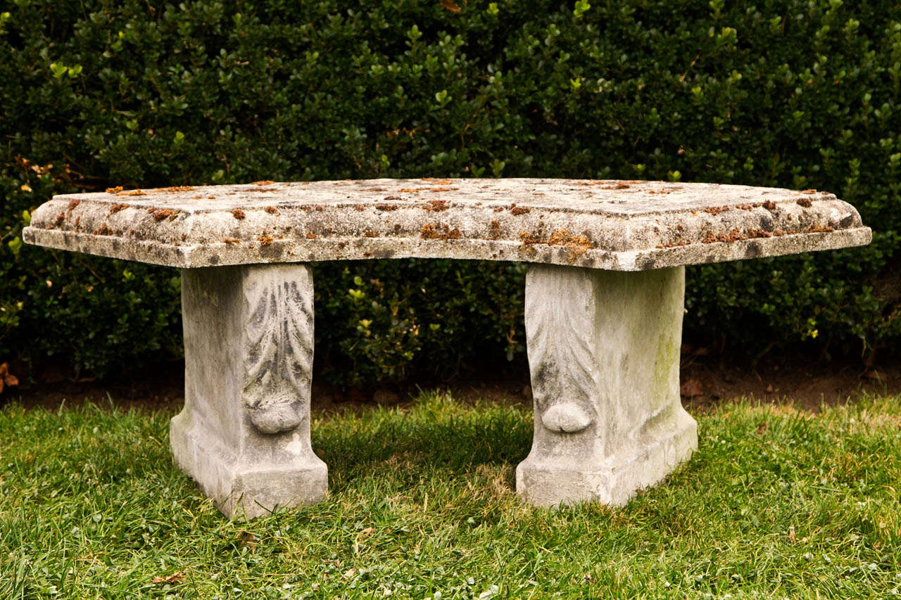 A composition stone curved bench, the supports ornamented with acanthus leaves.