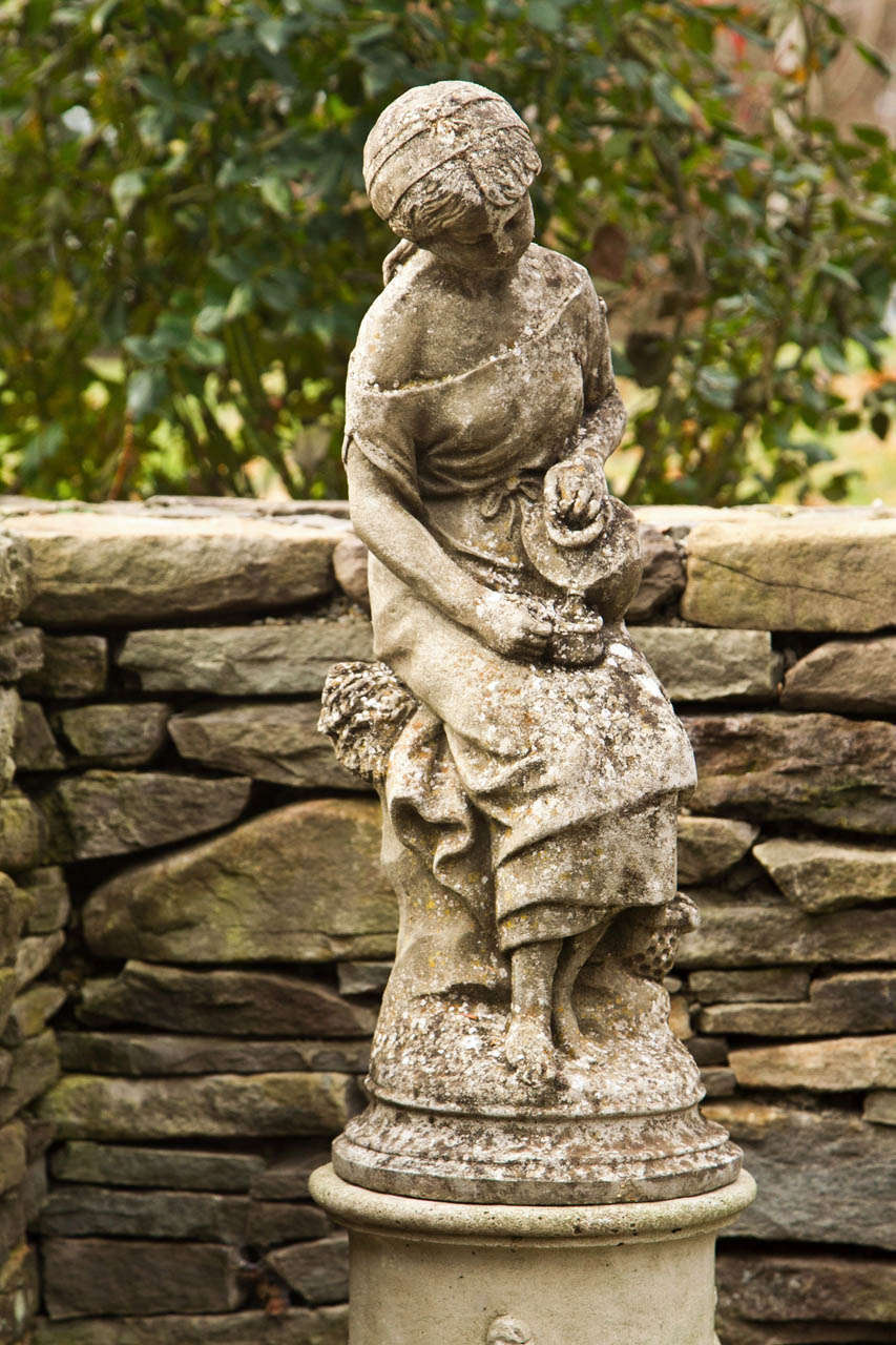 A composition stone figure of a young girl pouring water from a ewer.