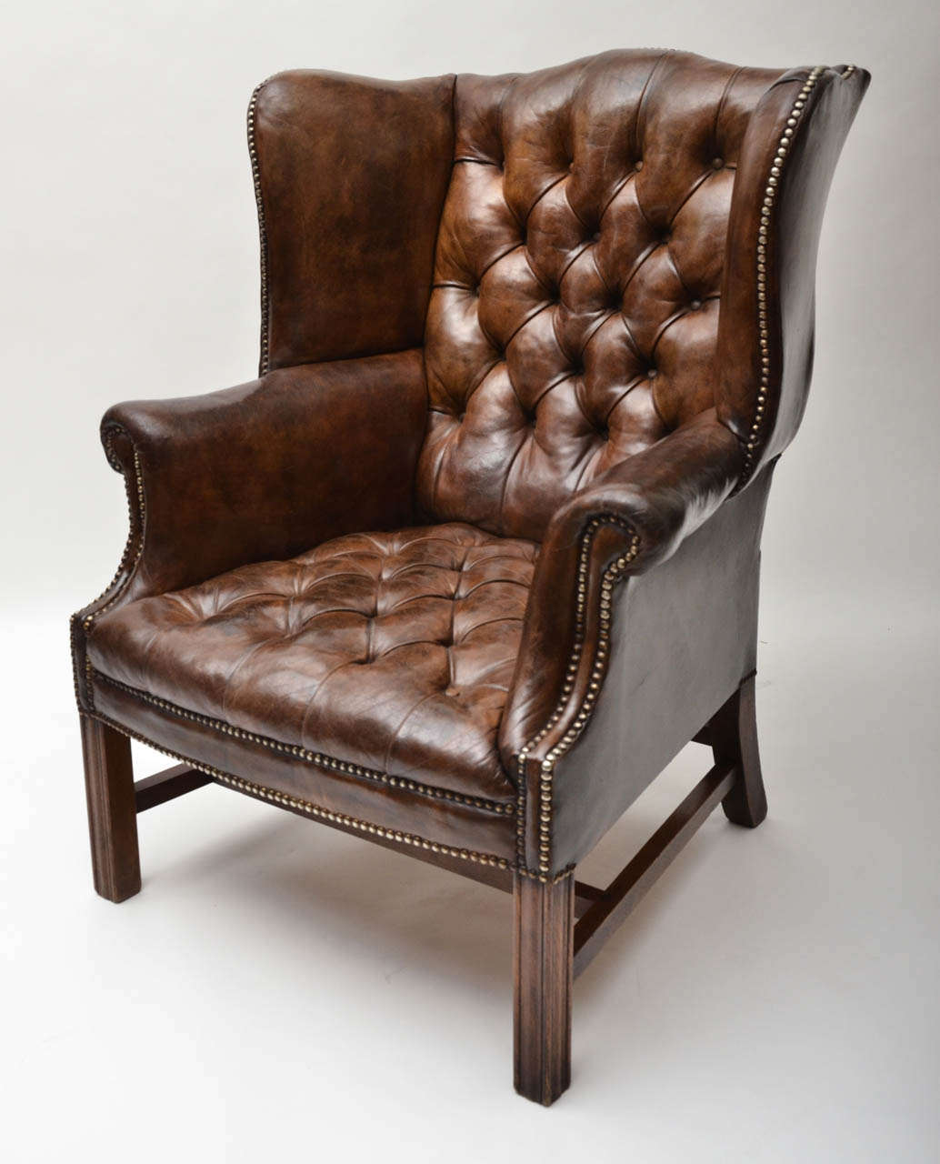 A 19th Century wing chair, original leather with tufted button-back and seat and original brass studs.