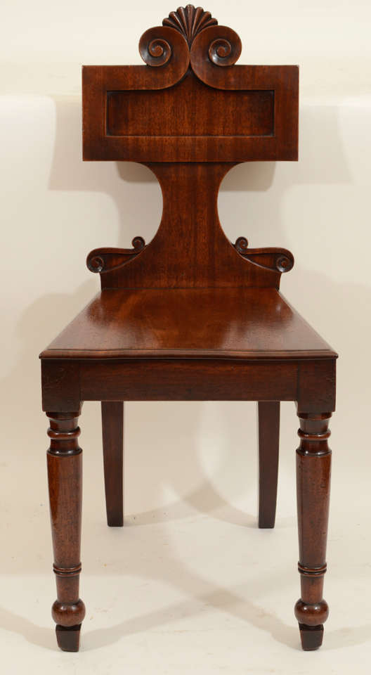 Pair of Distinctive Irish Regency Carved Mahogany Hall Chairs with Scrolled Back Detailing and Turned Front Legs.  Ireland, c. 1835

16 inches wide x 16 inches deep x 35 inches high