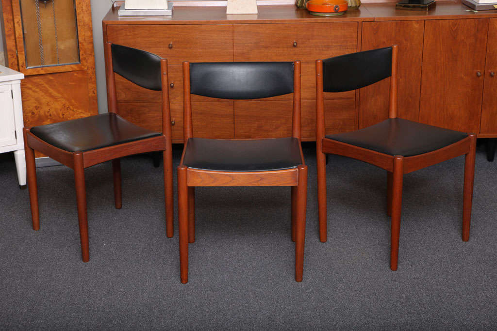 SOLD  Beautifully turned teak highlights this set of six Danish dining chairs that sport the original black leatherette seats and backs.  The teak of the side seat rails are nicely beveled adding a sculpted flair and smart visual to the profile.
