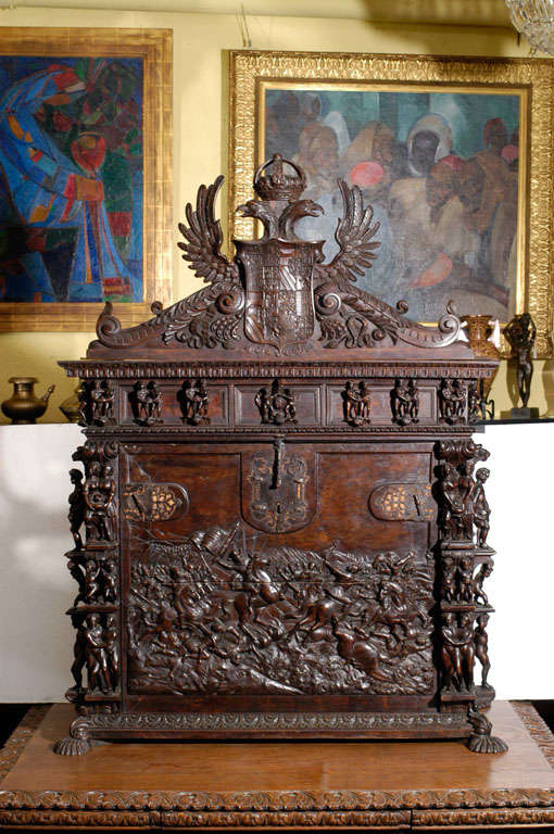 The detachable armorial shield crest is surmounted by winged eagles headed by a crown. With applied carved figures above a large door finely carved to show a battle scene (probably depicting the atrocites meted out on Native Americans by the Spanish