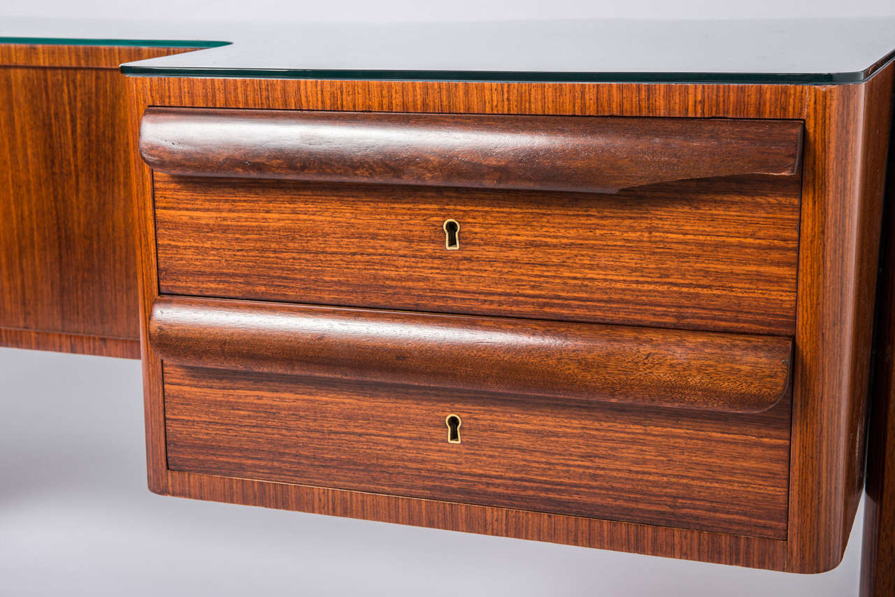 An Indian rosewood desk in the style of Paolo Buffa.
The glass top sat astride two pairs of asymmetrical tapering legs with brass sabots.
The lower rectangular top, blue enamelled set with glass.
The base beautifully veneered with the reverse