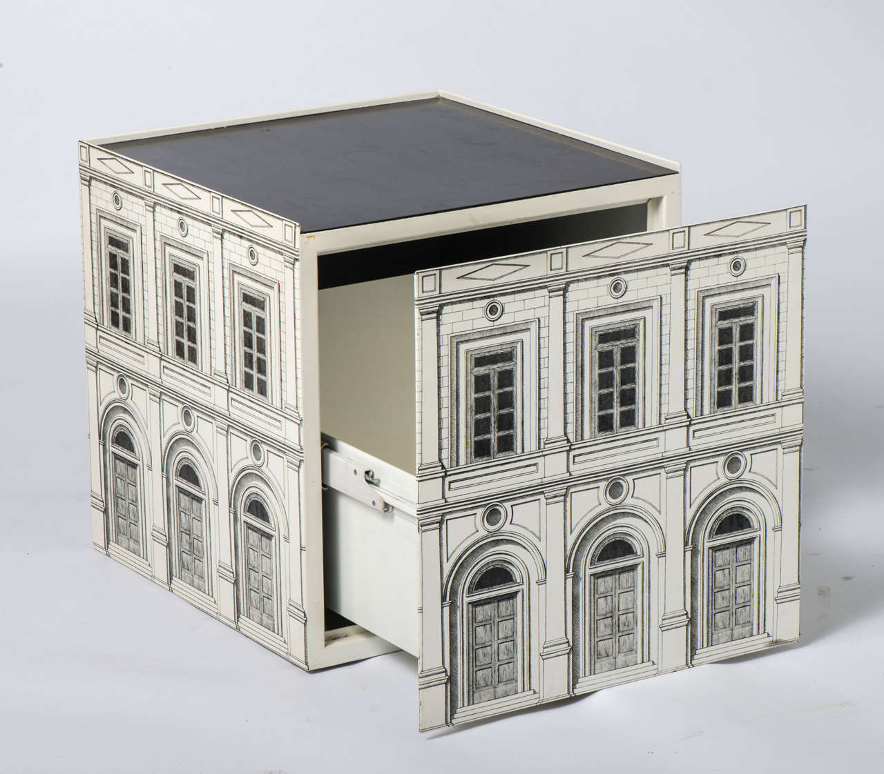 An Atelier Fornasetti Cube “Architettura” occasional table.
With single hidden drawer.
Lithographically printed metal.
Labelled to inside.
Italy, 1988-1989.