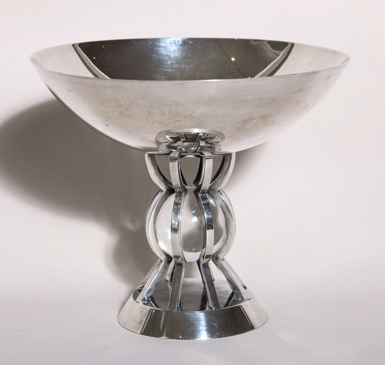 A circular sterling silver coupe on a pedestal with eight art-shaped rods, ornamented at the center with a crystal ball.
Hallmarked for 950 silver. 
Impressed Jean Puiforcat / Puiforcat poincon.
24.45 ozs. gross

Literature:
Francoise de