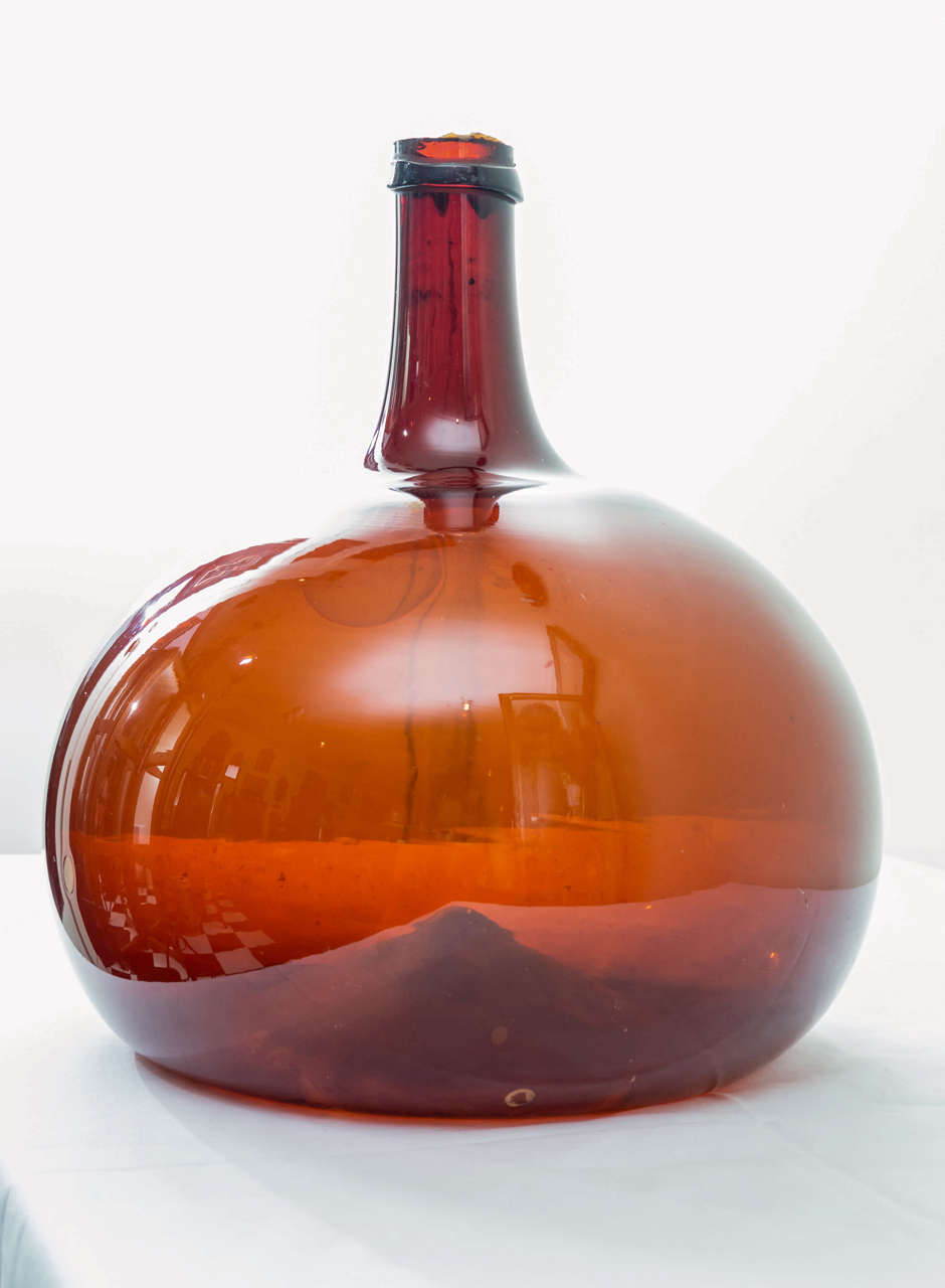 Late 18th century. French handblown Cognac bottle in amber tones. Interesting stretched and bubbled glass. The glass is very thin with perfect form and scale. Cut and drip applique top intact. Good abrasive wear on the bottom.