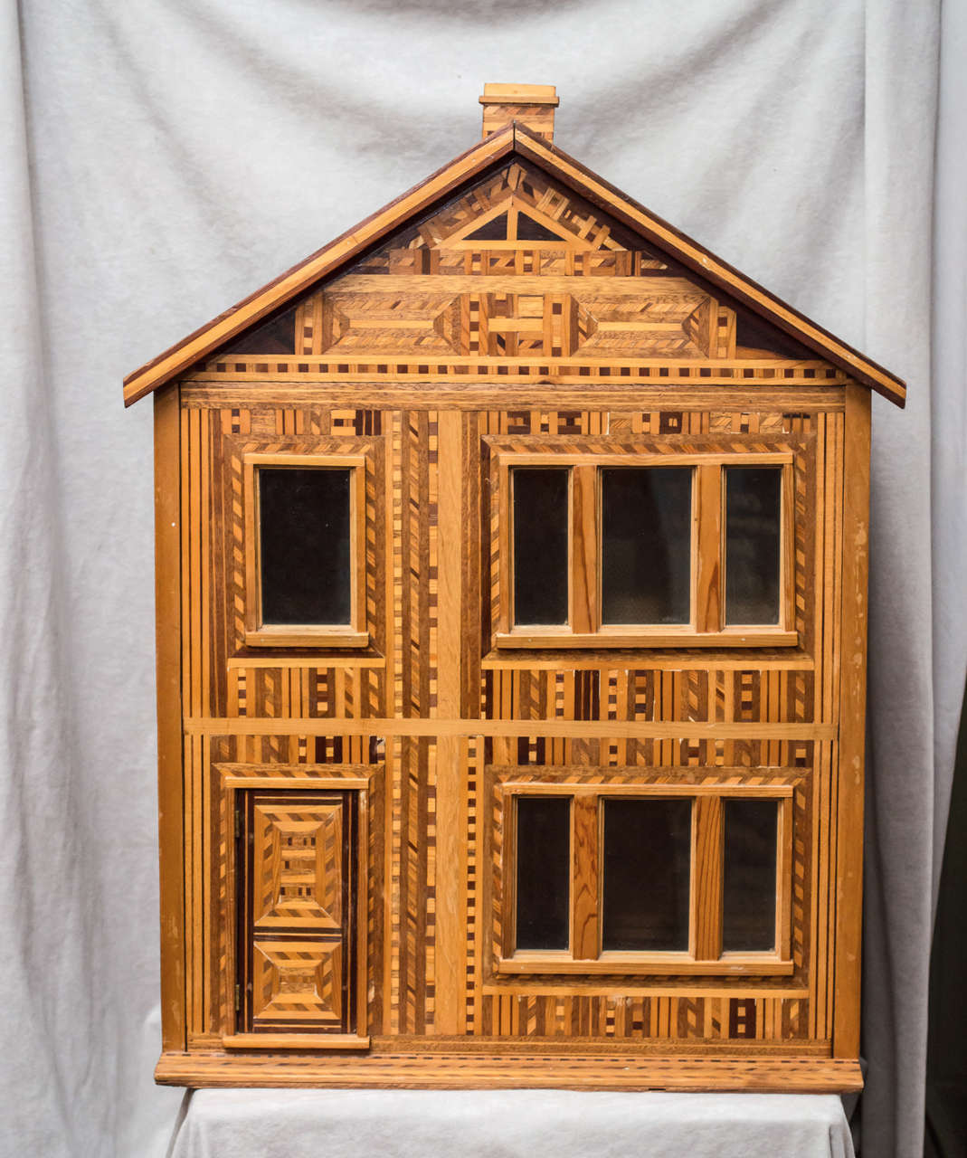 This very unusual doll house took someone a very long time to create. Loaded with marquetry and done in a very eye catching design. A unique and interesting antique.