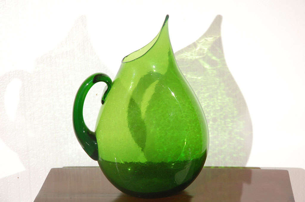 Flattened green glass blenko pitcher with elongated spout.